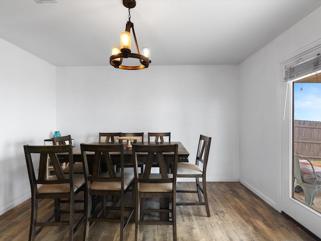 dining area featuring baseboards, dark wood finished floors, and an inviting chandelier