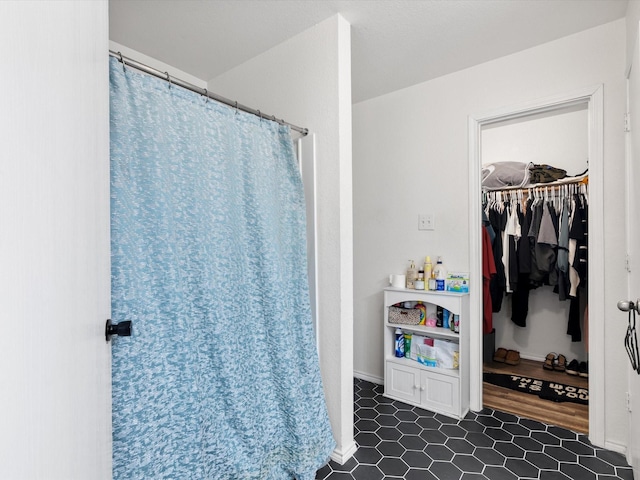 full bath with a spacious closet and tile patterned floors