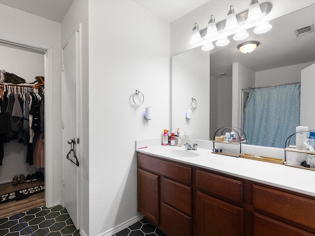 full bathroom with a walk in closet, visible vents, and vanity