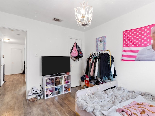 bedroom with a chandelier, a closet, wood finished floors, and visible vents