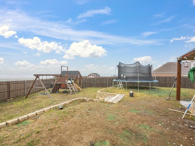 view of yard with a trampoline, a playground, and a fenced backyard