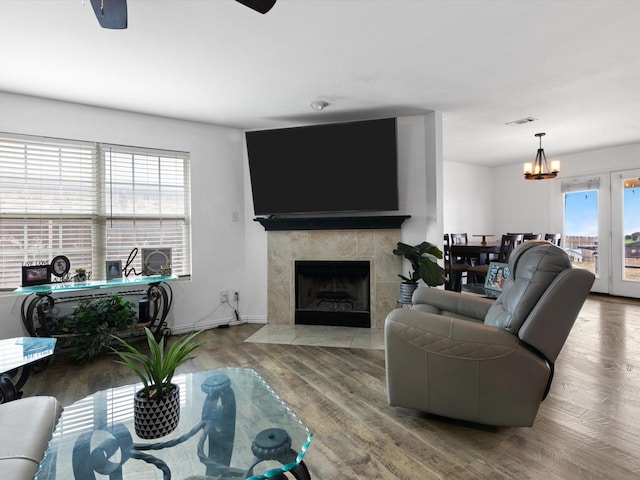 living area with visible vents, a tile fireplace, wood finished floors, and a wealth of natural light