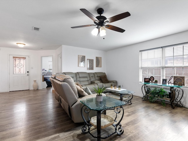 living area with baseboards, wood finished floors, visible vents, and a ceiling fan