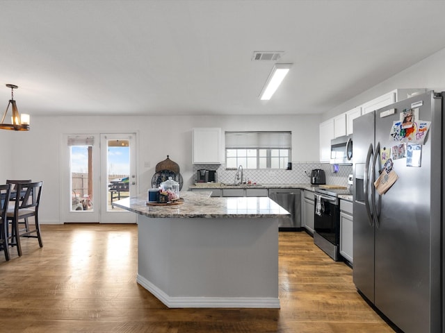 kitchen with visible vents, white cabinets, appliances with stainless steel finishes, a center island, and pendant lighting