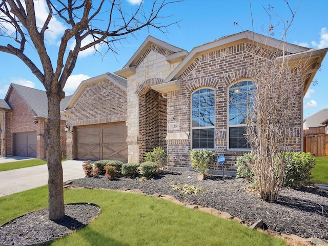 french country style house with a garage, concrete driveway, brick siding, and fence