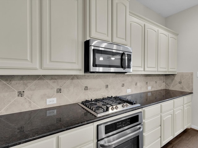 kitchen featuring tasteful backsplash, dark stone counters, dark wood-style floors, stainless steel appliances, and white cabinetry