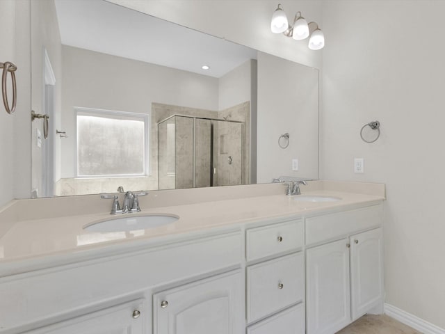 bathroom with double vanity, a shower stall, baseboards, and a sink