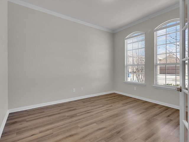 unfurnished room with baseboards, wood finished floors, a wealth of natural light, and crown molding