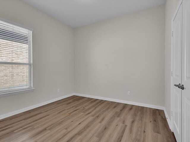 unfurnished bedroom with baseboards, a closet, and light wood-style floors