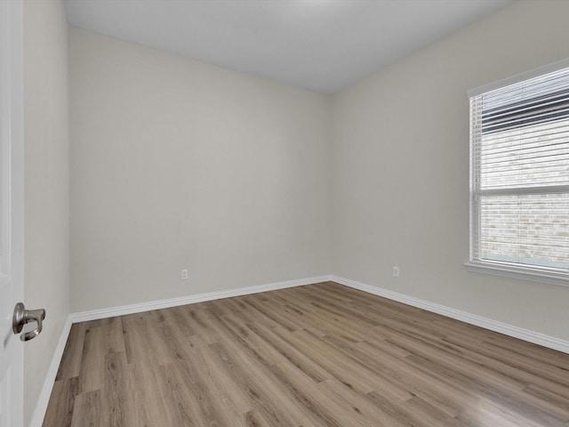 spare room featuring light wood-type flooring and baseboards