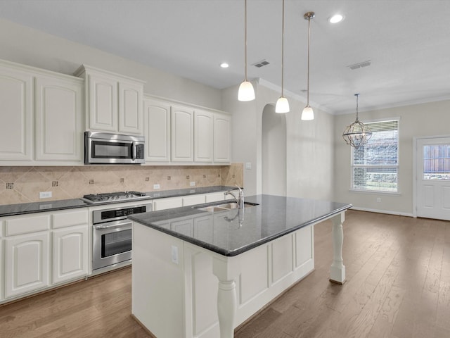 kitchen featuring arched walkways, a sink, visible vents, appliances with stainless steel finishes, and tasteful backsplash