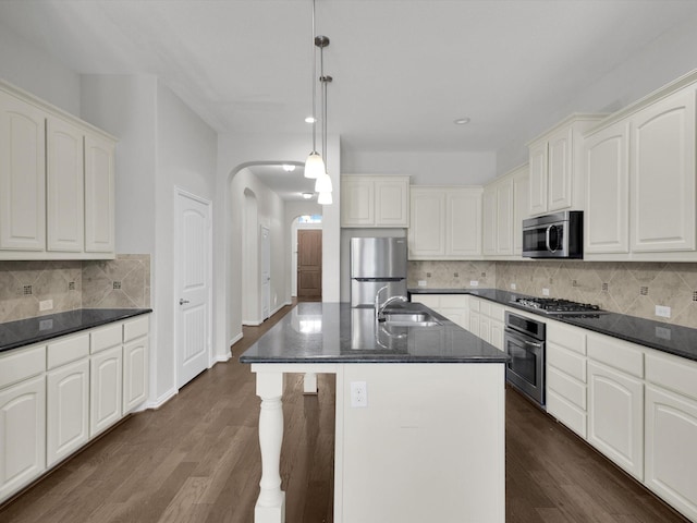 kitchen featuring stainless steel appliances, arched walkways, dark wood-type flooring, and a sink