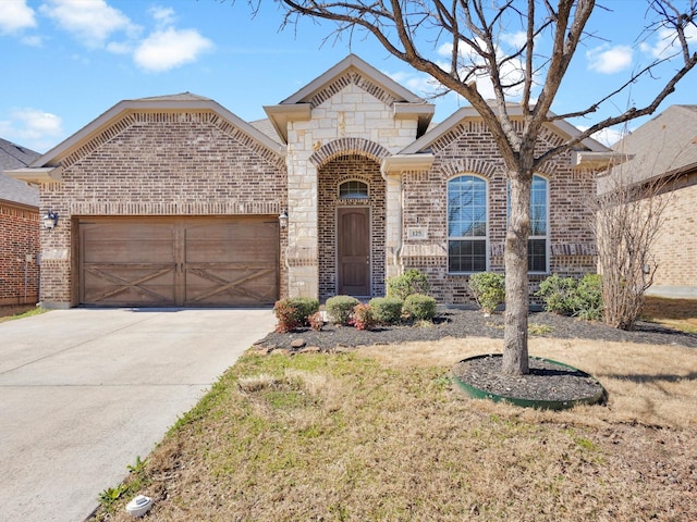 french provincial home featuring stone siding, brick siding, driveway, and an attached garage