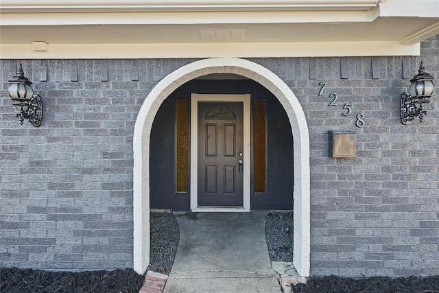 view of exterior entry featuring brick siding