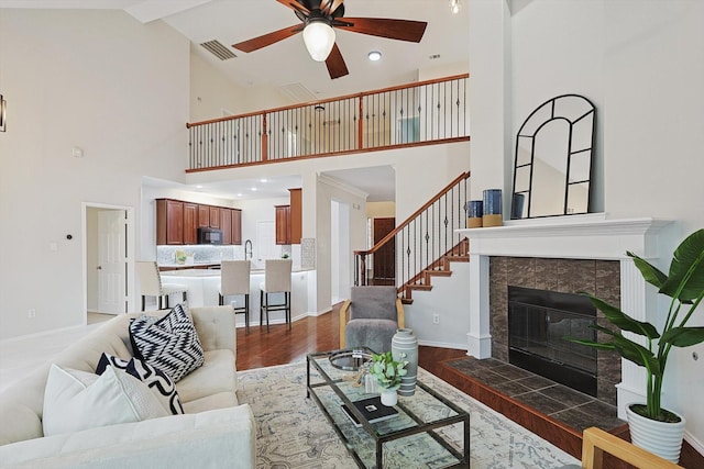 living room with a fireplace, dark wood finished floors, visible vents, a ceiling fan, and baseboards