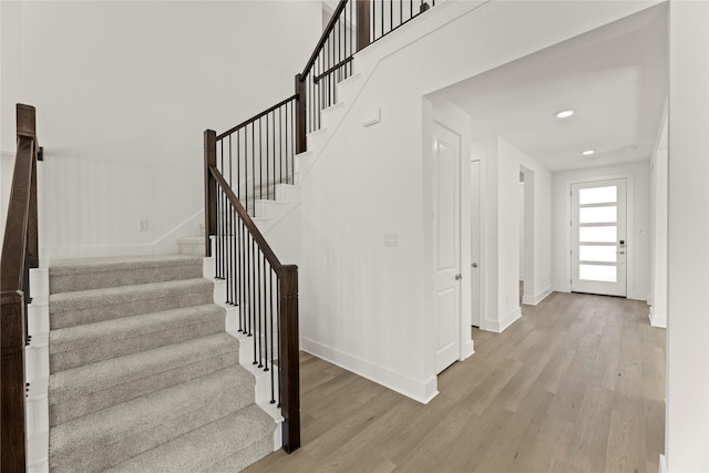 staircase with recessed lighting, wood finished floors, and baseboards