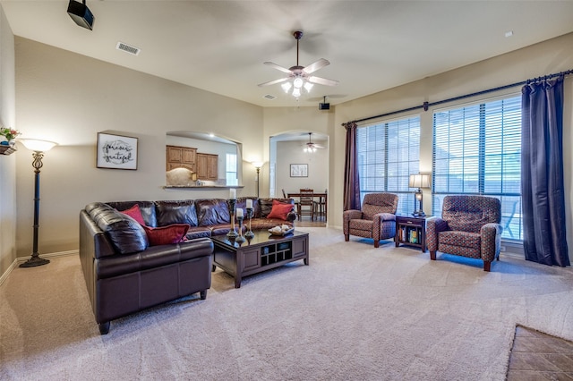 living room featuring arched walkways, ceiling fan, light carpet, and visible vents