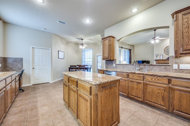 kitchen featuring light tile patterned floors, a kitchen island, visible vents, and brown cabinetry