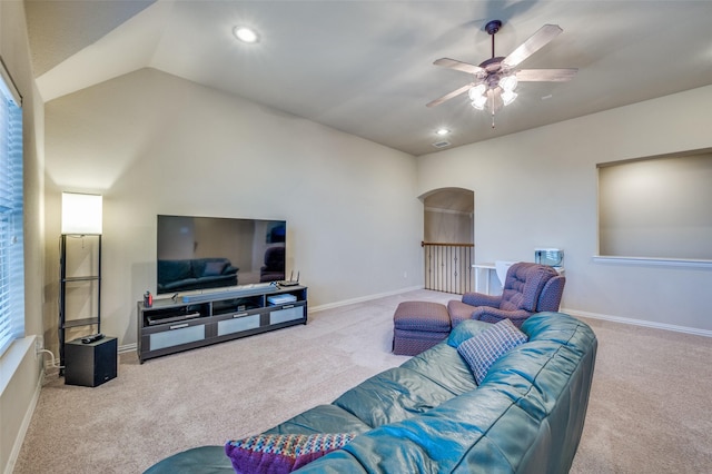 living area with arched walkways, light colored carpet, lofted ceiling, and baseboards