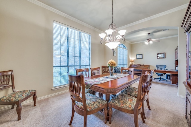 dining room with baseboards, arched walkways, a ceiling fan, light colored carpet, and crown molding