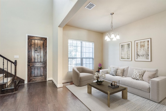 living room featuring wood finished floors, visible vents, baseboards, stairs, and an inviting chandelier