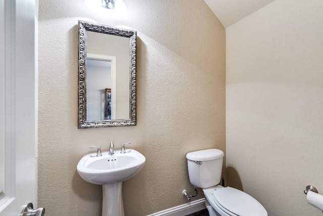 bathroom featuring toilet and a textured wall