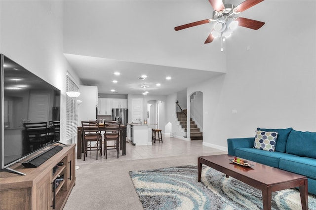 living room with arched walkways, ceiling fan, recessed lighting, baseboards, and stairs