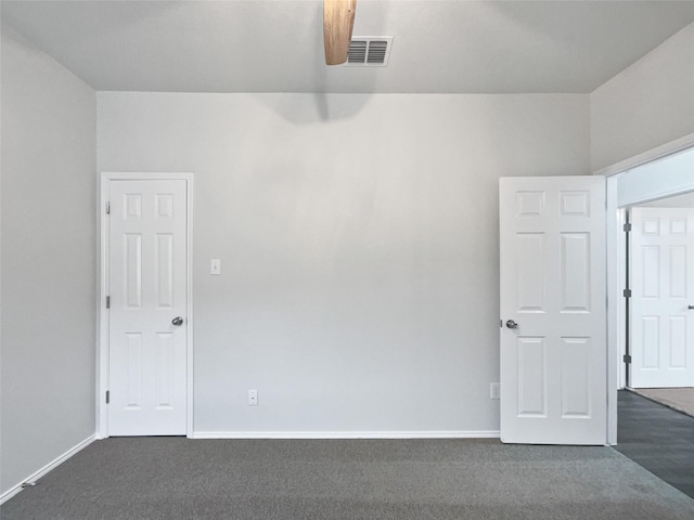 unfurnished room featuring dark colored carpet, visible vents, and baseboards