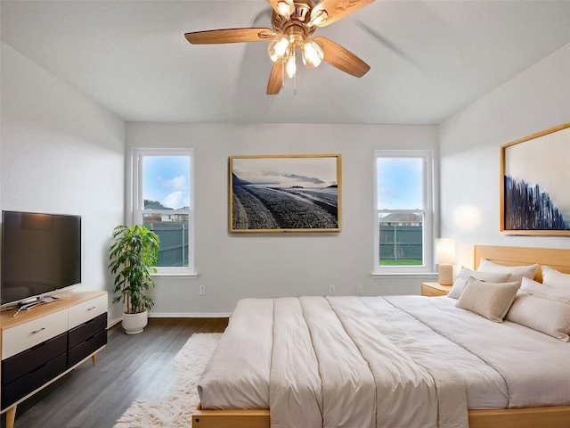 bedroom with a ceiling fan, dark wood finished floors, and baseboards