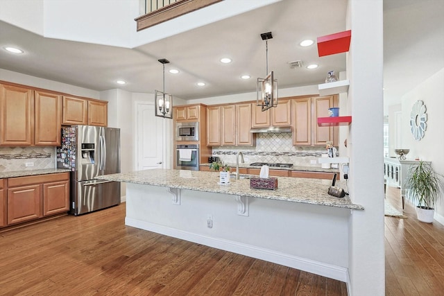 kitchen with visible vents, light stone counters, a kitchen breakfast bar, hanging light fixtures, and stainless steel appliances