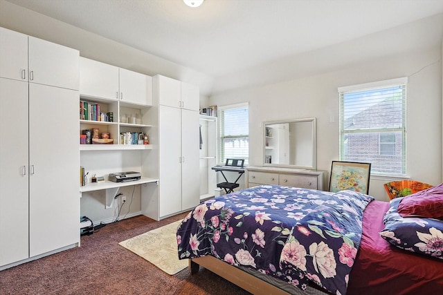 bedroom with dark colored carpet and built in desk