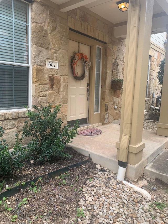 view of exterior entry with a porch and stone siding