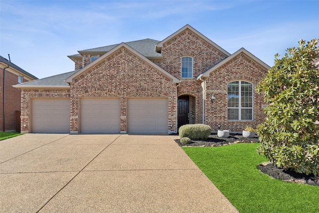 traditional home with roof with shingles, brick siding, an attached garage, a front yard, and driveway