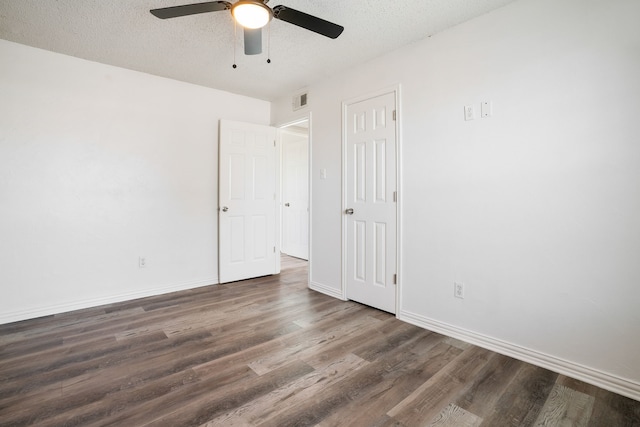 unfurnished bedroom featuring dark wood-style flooring, visible vents, a textured ceiling, and baseboards