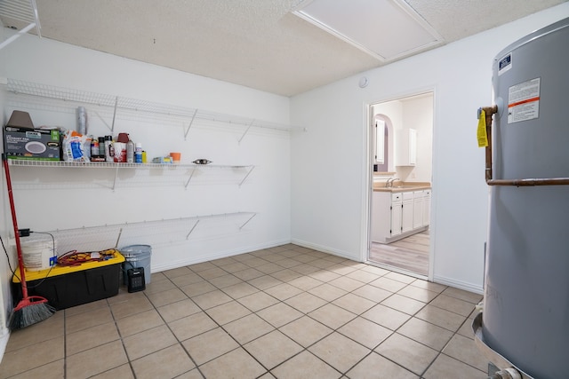 clothes washing area with light tile patterned floors, laundry area, baseboards, a textured ceiling, and a sink