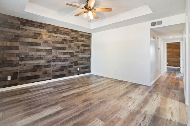 empty room featuring dark wood finished floors, a raised ceiling, and visible vents