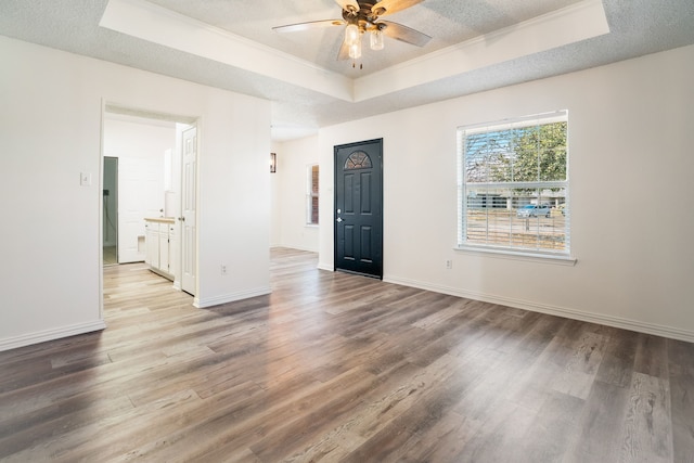 spare room with a textured ceiling, a tray ceiling, wood finished floors, and baseboards