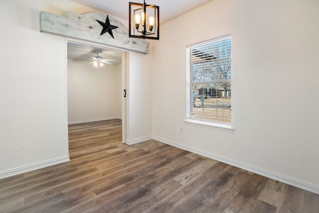 unfurnished dining area featuring a chandelier, wood finished floors, and baseboards