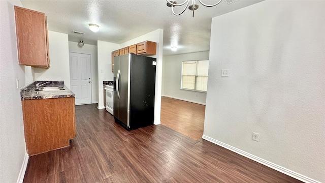 kitchen featuring dark wood-type flooring, a sink, white range with gas cooktop, stainless steel fridge with ice dispenser, and brown cabinetry