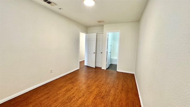 unfurnished bedroom with dark wood-type flooring, visible vents, and baseboards