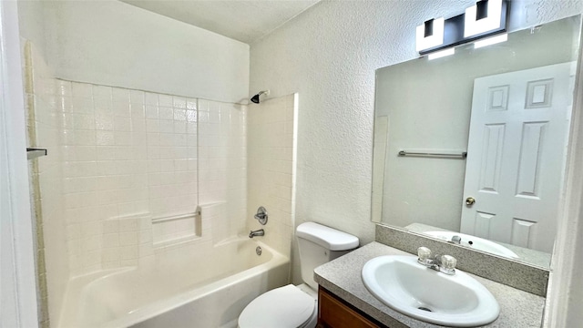 full bath with toilet, vanity, tub / shower combination, and a textured wall