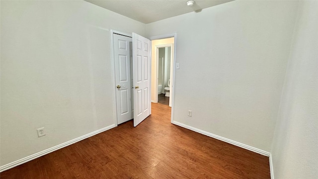 spare room featuring baseboards and wood finished floors