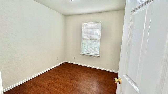 unfurnished room featuring baseboards and dark wood-style flooring