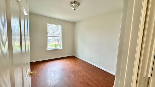 unfurnished room with baseboards and dark wood-style flooring