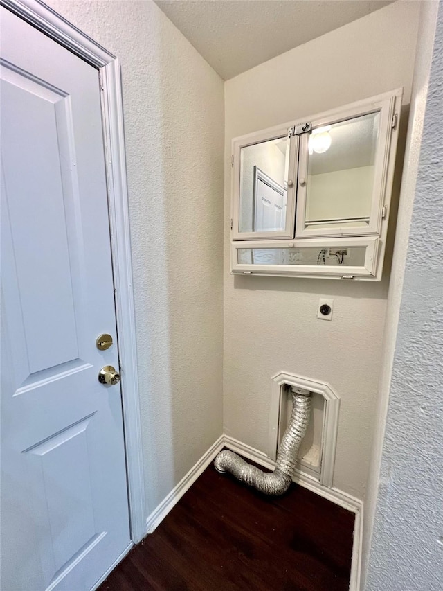 laundry area featuring a textured wall, laundry area, baseboards, dark wood-style floors, and electric dryer hookup