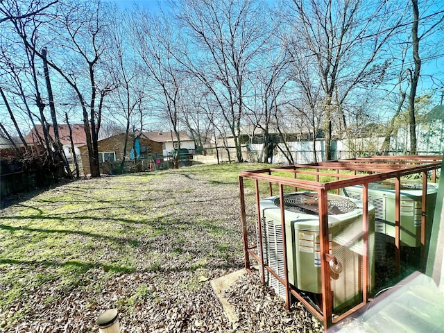 view of yard with central AC, fence, and a residential view