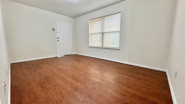 spare room with dark wood-type flooring and baseboards