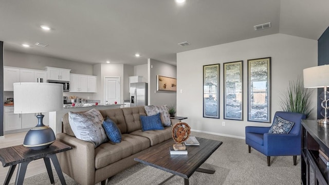 living area featuring recessed lighting, visible vents, and light carpet