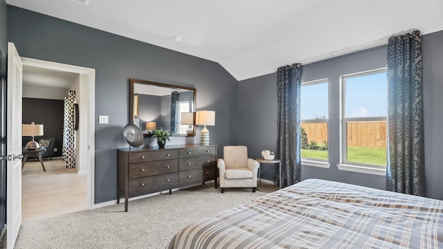 bedroom featuring lofted ceiling, baseboards, and light colored carpet