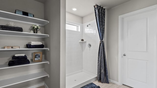 bathroom with a stall shower, wood finished floors, and baseboards